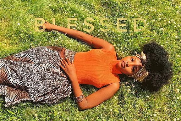 Andrea laying in the grass with the word 'blessed' typed on top of her.