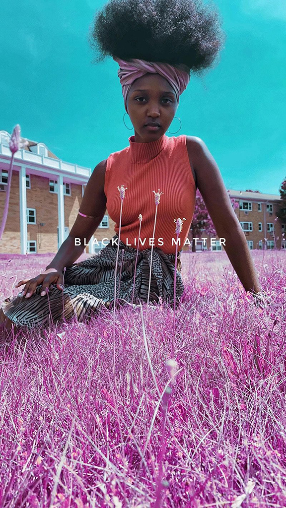 Andrea sitting in grass with the words 'black lives matter' types above her.